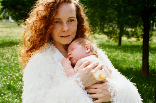 A mother holding a baby in a park on a sunny day