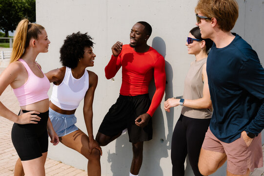 Diverse group of runner friends, talking quietly in a public park