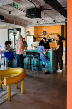 Coworkers Socializing Around Office Kitchen Island