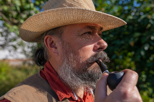 Bearded Man Smoking a Pipe Outdoors