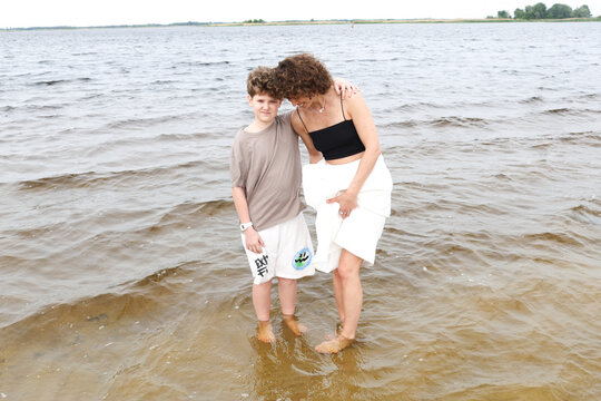 A mother and son are walking by the river.