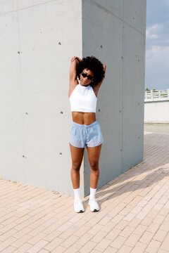 A sporty young woman, posing in sportswear in a public park