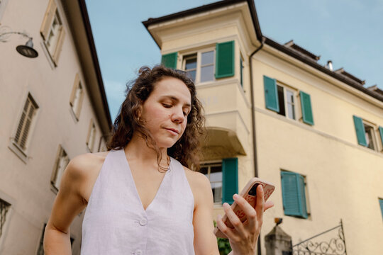 Woman checking phone in Italian old town during summer trip