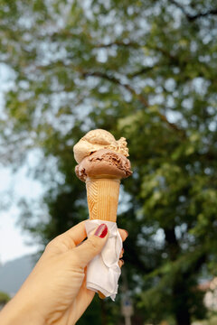 Hand holding ice cream gelato cone during summer trip in Merano