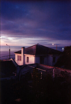 Coastal house near the ocean under a purple twilight sky on film
