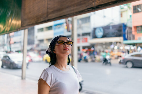 Young Woman in Sunglasses Looking Up on City Street