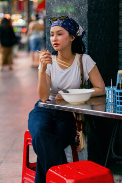 Young Asian Woman Eating Street Noodles At Outdoor Cafe