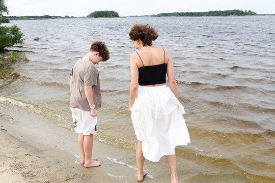 A mother and son are walking by the river.