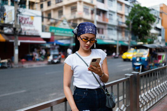 Young Woman Using Smartphone On Urban Street