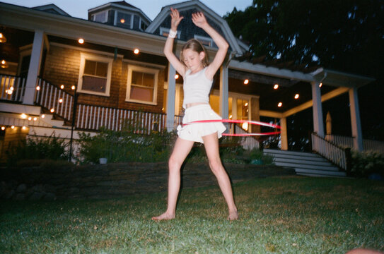 Young Girl with hula hoop in backyard of home film dusk