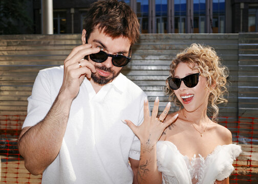 Bride and groom showing wedding ring and wearing sunglasses