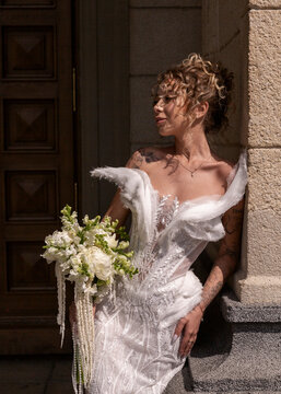 Bride in lace wedding dress holding bouquet in sunlight