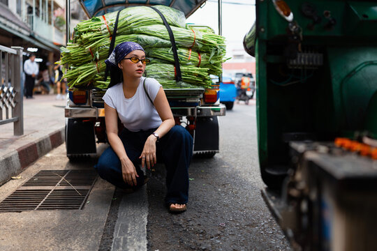 Young Woman Squatting Next to Vegetable Truck