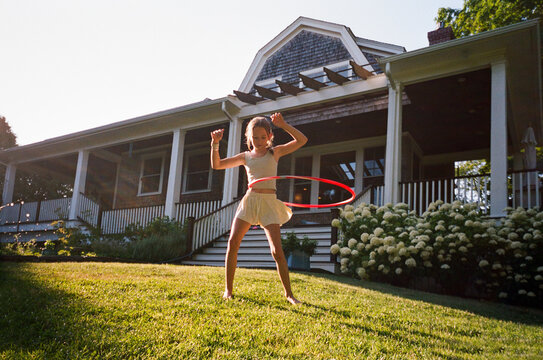 Young Girl with hula hoop spin in backyard of home film