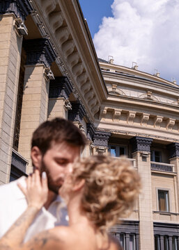 Bride and groom embrace in front of historic architecture