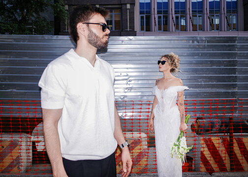 Bride and groom standing in urban setting wearing sunglasses