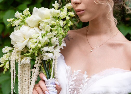 Bride holding white wedding bouquet outdoors