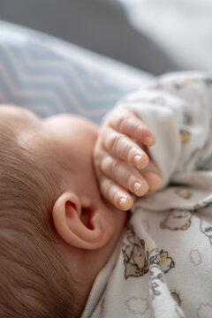 Baby Hand Touching Cheek While Resting on a Blanket