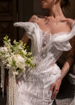 Bride in embroidered wedding dress holding white flower bouquet