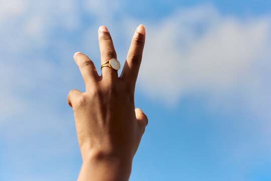 Hand reaching out towards a Blue Sky