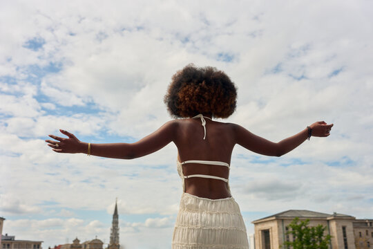 Woman With Arms Open Near City Buildings on Sunny Day