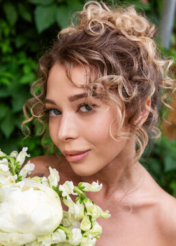 Bride with curly updo hairstyle holding white flower bouquet
