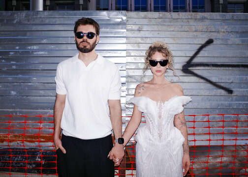 Bride and groom holding hands wearing sunglasses outdoors