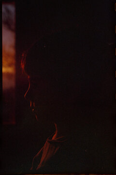 Moody silhouette profile of a child near window at golden hour