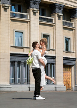 Bride and groom embrace outside urban building on wedding day