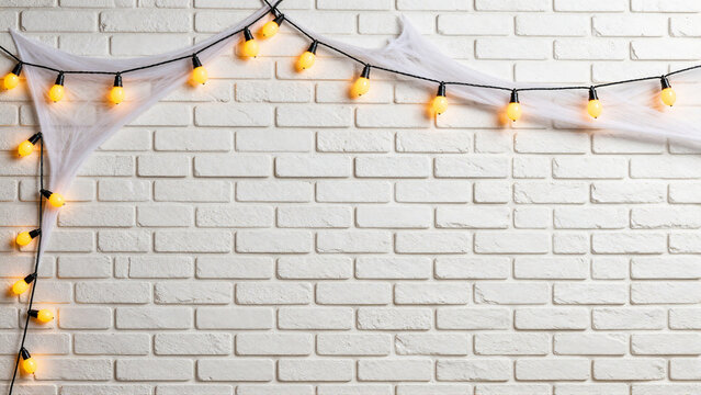 Spooky Halloween String Lights and Cobwebs on White Brick Wall