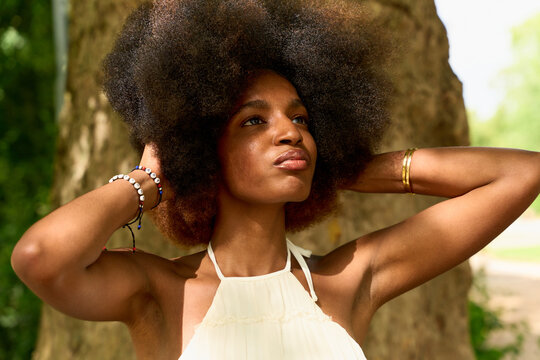 Young Woman With Afro Hairstyle Poses Outdoors in Bright Sunlight