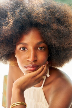 Woman With Curly Hair Gazes Thoughtfully While Resting on Hand