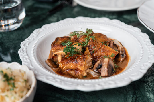 Roast Chicken Dish Served With Mushrooms and Herbs on a White Plate