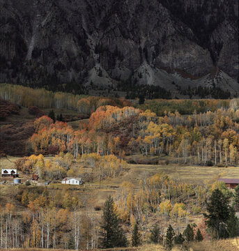 Beautiful scenic view of a rural mountain ranch with autumn golden aspen forest at sunset