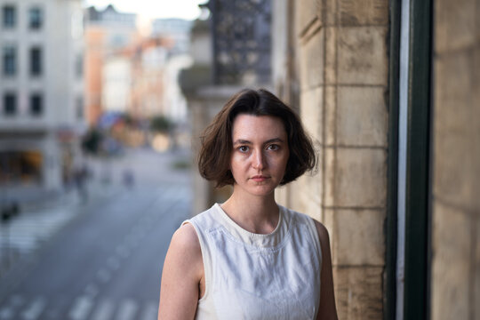 Young Woman Stands Near a Building in a City During the Day