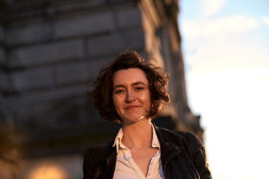 Woman With Curly Hair Smiles Outdoors During Sunset
