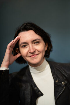 Woman Sitting and Smiling With Hand on Forehead in Indoor Space
