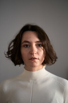 A Woman Stands Indoors With a Neutral Background