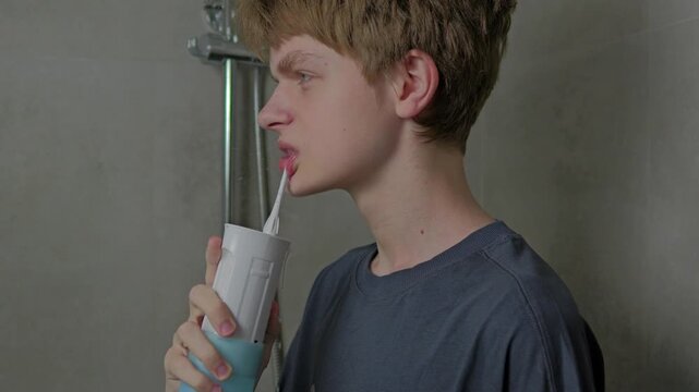 Teen Boy Cleaning Teeth with Water Flosser During Morning Hygiene Routine