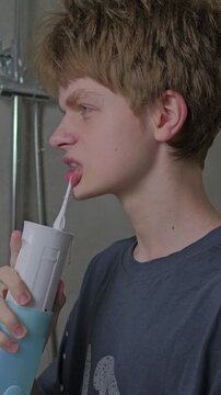 Teen Boy Cleaning Teeth with Water Flosser During Morning Hygiene Routine