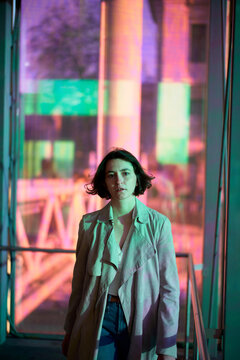 Woman Stands Inside a Colorful Building With Bright Lights