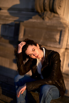 Woman Sitting on Steps at Sunset in Urban Setting