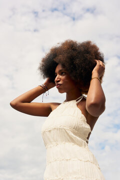 Woman With Curly Hair Posing Outdoors Under Cloudy Sky