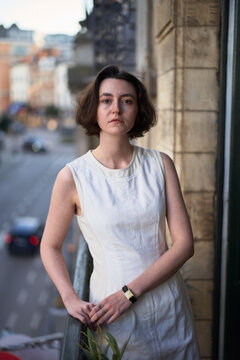 Woman Stands on Balcony in Urban Setting During Sunset