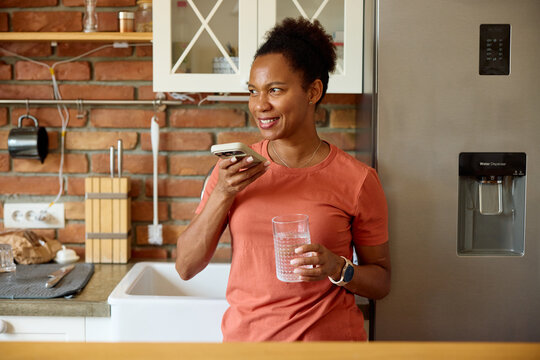 Woman is in the kitchen, speaking to her phone.