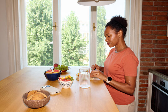 Pleased woman prepares fruit salad at home