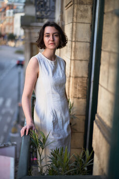 Woman Stands on Balcony in City During Day
