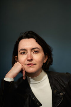 Person Sits With Chin on Hand in Front of Dark Blue Background