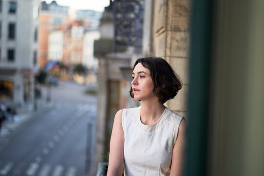 Woman Standing on Balcony in Urban Area Looking Away