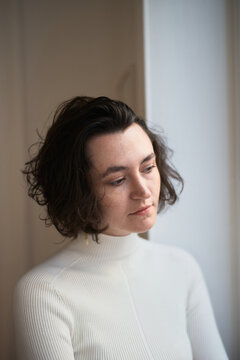 Woman With Curly Hair Looking Thoughtful by a Window